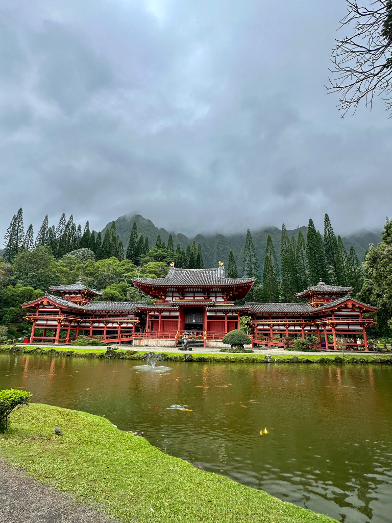 Byodo-In Temple in Kaneohe Oahu reflected across a peaceful pond with misty Koʻolau mountains in the background